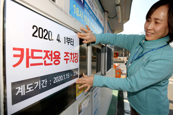 ▲ 수원시청 본관주차장에서 수원도시공사 직원이 신용카드 전용결제를 알리는 안내표를 주차부스에 부착하고 있다.