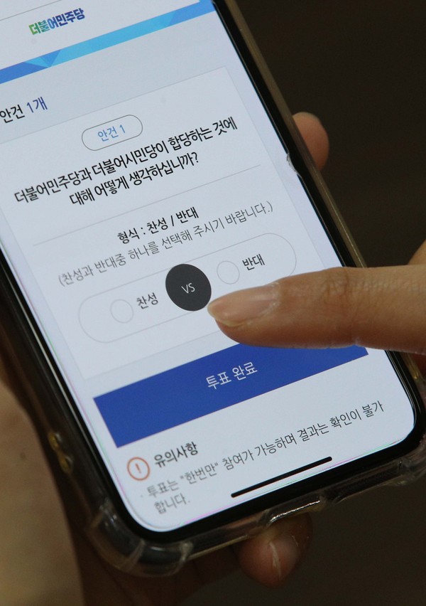 더불어민주당 당원이 7일 오전 국회에서 스마트폰으로 더불어민주당-더불어시민당 합당 여부를 묻는 권리당원 투표를 하고 있다. 2020.05.07.