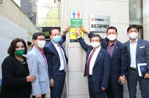 ▲ 유동균 마포구청장이 마포구 내 4곳의 동 주민센터에서 개방화장실 표지판을 부착하고 기념사진을 촬영하고 있다.