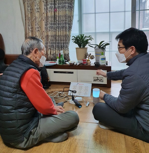 ▲ 동대문구보건소 직원이 어르신에게 인공지능 돌봄 스피커 로봇 아리아 사용법을 안내하고 있다.