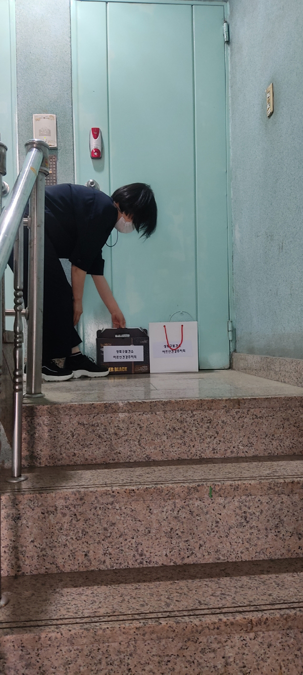 ▲ 건강주치의 방문간호사가 어르신에게 비대면으로 생활물품을 전달하고 있는 모습.
