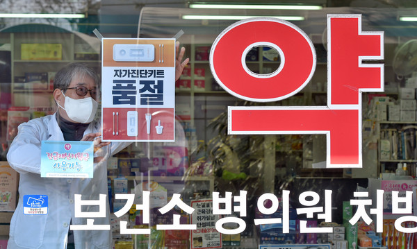 ▲ 대구 수성구의 한 약국에 약사가 품절 안내문을 붙이고 있다. /뉴시스