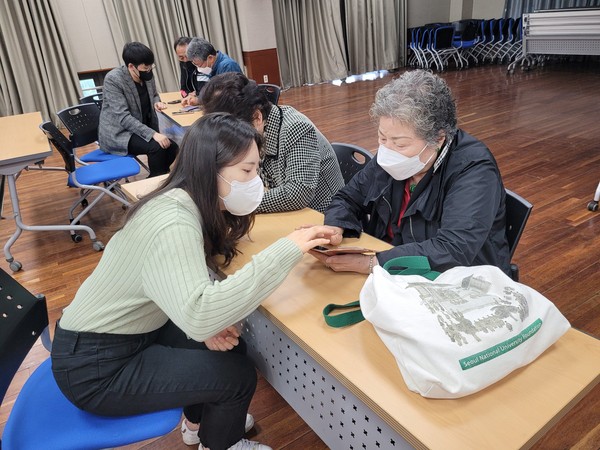 ▲ 월곡1동 주민센터에서 어르신을 대상으로 1:1 맞춤형 스마트폰 사용법을 교육하고 있는 국민대 학생.