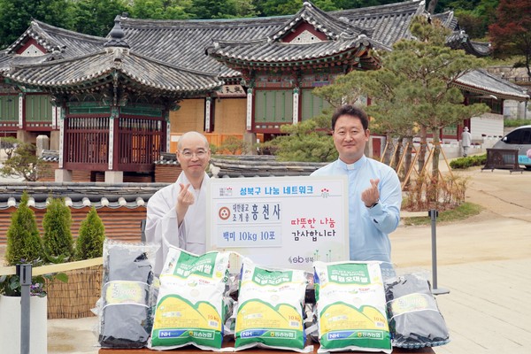 ▲ 흥천사 경내에서 진행된 쌀 기증식 후 청년을 위한 응원의 손하트를 하고 있는 흥천사 각밀 주지스님(왼쪽)과 청년밥상 문간의 가브리엘신부님(오른쪽).