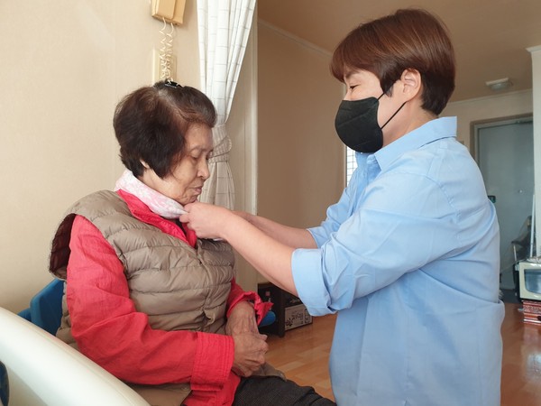 ▲ 지역사회통합돌봄 어르신에 스카프 매드리는 모습.