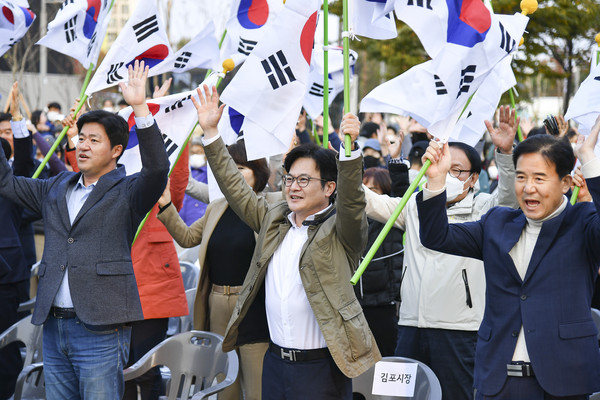 ▲ 김병수(가운데) 시장이 오라니장터를 찾아 양손에 태극기를 들고 주민들과 함께 만세 부르고 있다.