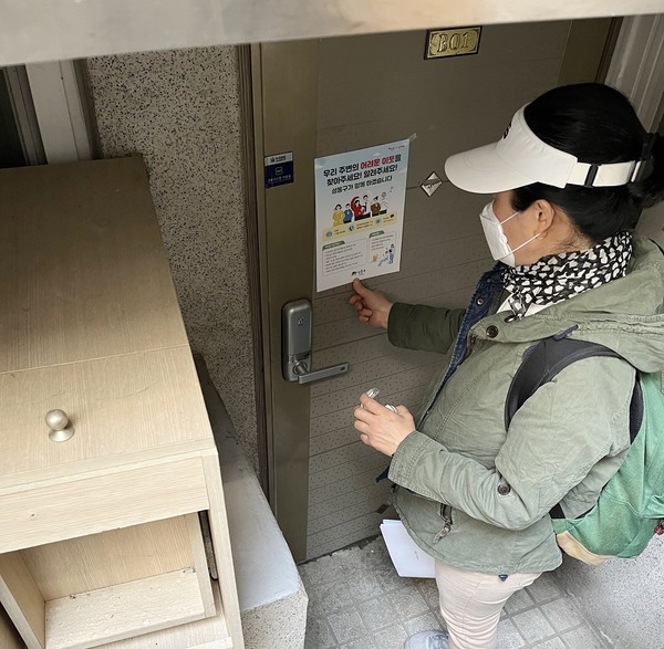 ▲ 반지하 가구에 복지사각지대 발굴 홍보물을 부착하고 있는 위기가구 촘촘발굴단.