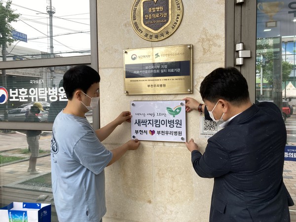 ▲ 부천우리병원 관계자와 담당 공무원이 부천우리병원 입구에 현판을 부착하고 있다.