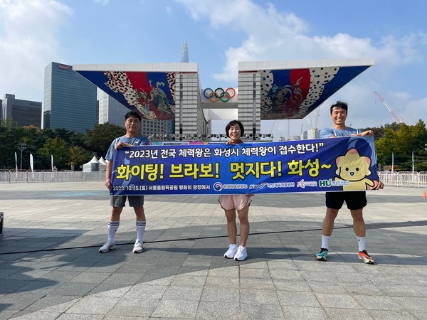 ▲ 올림픽공원 평화의 광장 앞에서 화성시 체력왕 대표로 전국대회에 참여한 시민 3명이 현수막을 사진을 찍고 있다.