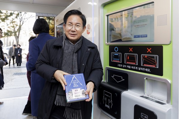 ▲ 박강수 마포구청장이 마포상암 스마트도서관 무인대출반납기에서 책을 빌리고 있다.