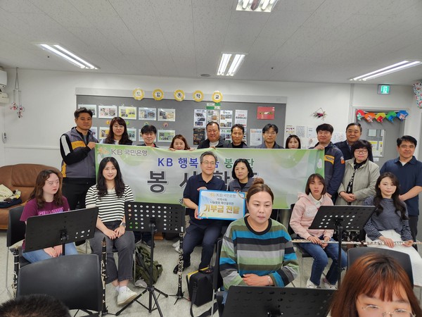 ▲ KB국민은행의 직원 및 가족이 봉사활동 관련 기념촬영을 하고 있다.
