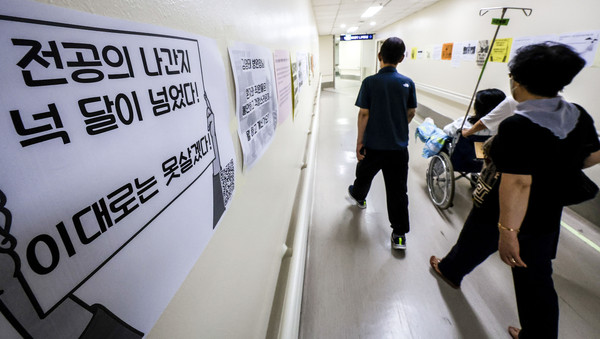 ▲ 서울시내 대학병원에 붙은 전공의 집단행동 중단을 촉구하는 인쇄물 옆으로 환자와 보호자들이 이동하고 있다.