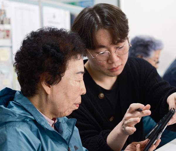 ▲ 고려대학교 봉사동아리 ‘안다미로’ 학생이 어르신에게 스마트폰 활용법을 알려주고 있다.