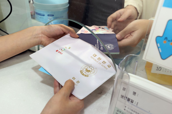 ▲ 교부 중인 여권 케이스와 여권, 전자여권 홍보물의 모습.