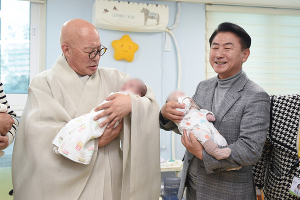 ▲ 김동근 시장이 대한불교조계종의 자비 나눔 행사에 참석해 총무원장 진우스님과 아기들을 안고 있다.
