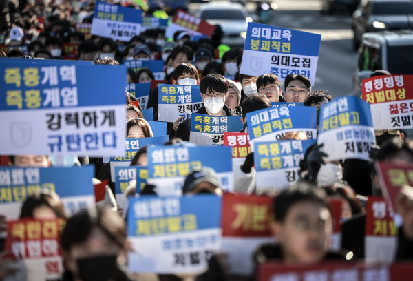 ▲ 지난 8일 서울 종로구 대학로에서 열린 서울대병원 전공의협의회 비상대책위원회 ‘젊은 의사 의료계엄 규탄 집회’에서 사직 전공의를 비롯한 젊은 의사들이 피켓을 들고 있다. /뉴시스