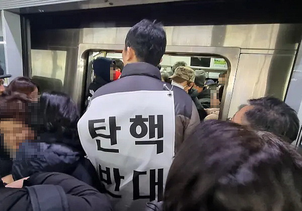 ▲ 윤석열 대통령 2차 탄핵소추안 국회 본회의 표결이 이뤄진 14일 서울 여의도 국회 앞과 광화문 광장에서 탄핵 찬반 집회가 열린 가운데 지하철에서 '탄핵 반대' 플래카드를 등에 걸고 시민들을 위협하는 남성에 대한 제보가 나왔다. (사진=유튜브 채널 '촛불행동tv') /뉴시스