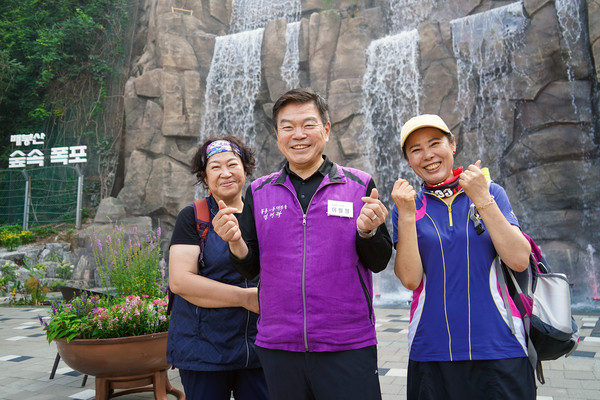▲ 공약에 따라 조성된 폭포앞에서 기념촬영하는 구청장과 구민들.