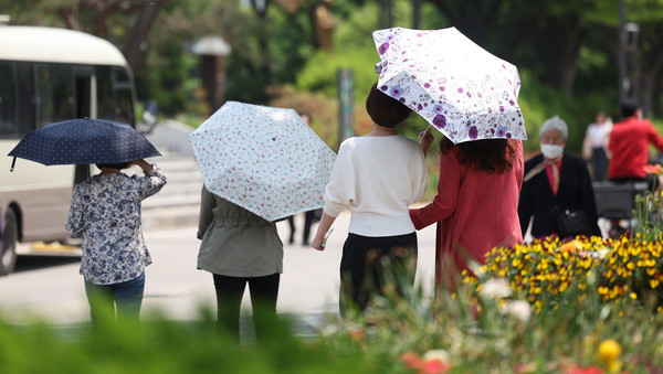 ▲ 서울 낮 최고기온이 25도 이상 오르며 더운 날씨를 보인 13일 서울 동작구 보라매공원에서 시민들이 양산을 쓰고 산책하고 있다. /뉴시스