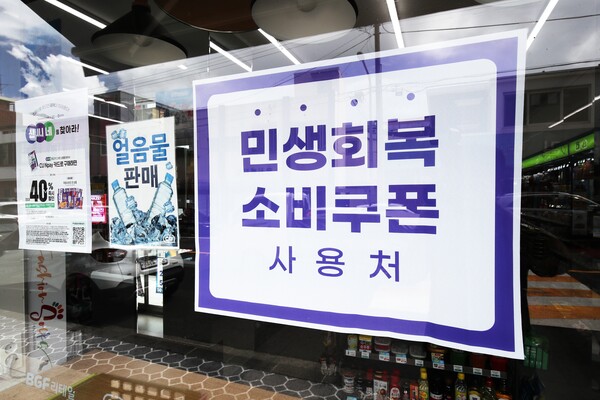 ▲ 민생회복 소비쿠폰 1차 지급을 시작한 21일 오전 제주시 일도1동의 한 편의점 창문에 민생회복 소비쿠폰 사용처를 알리는 현수막이 게시돼 있다. /뉴시스