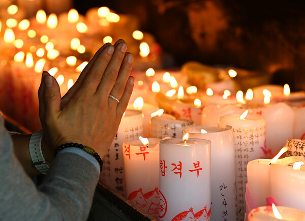 ▲ 2026학년도 대학수학능력시험(11월13일)을 한달 앞둔 13일 경기 화성시 용주사에서 수험생 학부모가 자녀의 수능 고득점을 기원하며 촛불 앞에서 기도하고 있다. /뉴시스