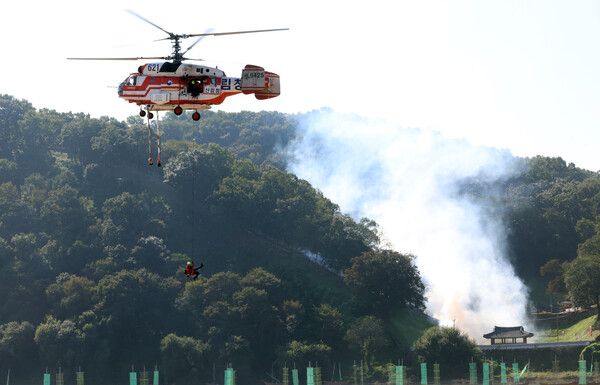 ▲ 지난 10월 22일 충남 공주시 금강변에서 열린 2025 산불진화 통합훈련에서 산불진화요원이 헬기레펠을 하고 있다. /뉴시스