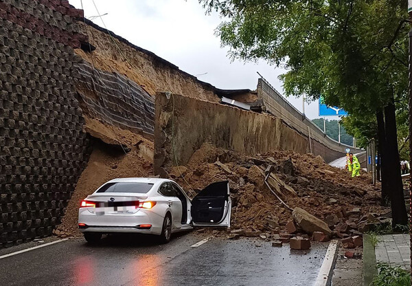 ▲ 수도권 등 중부지역에 호우주의보가 발효된 지난 7월 16일 경기 오산시 가장교차로 옹벽이 도로로 무너져 차량을 덮치는 사고가 발생해 소방당국이 대응 1단계를 발령, 구조작업을 벌이고 있다. (사진=경기도소방재난본부 제공)